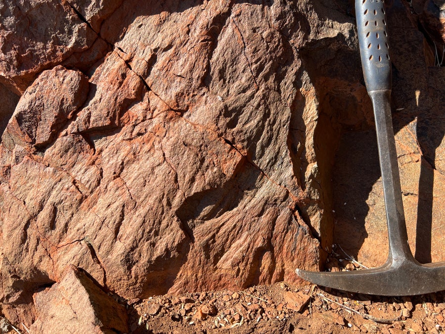 A hammer leans against a rock with delicate shatter cones.