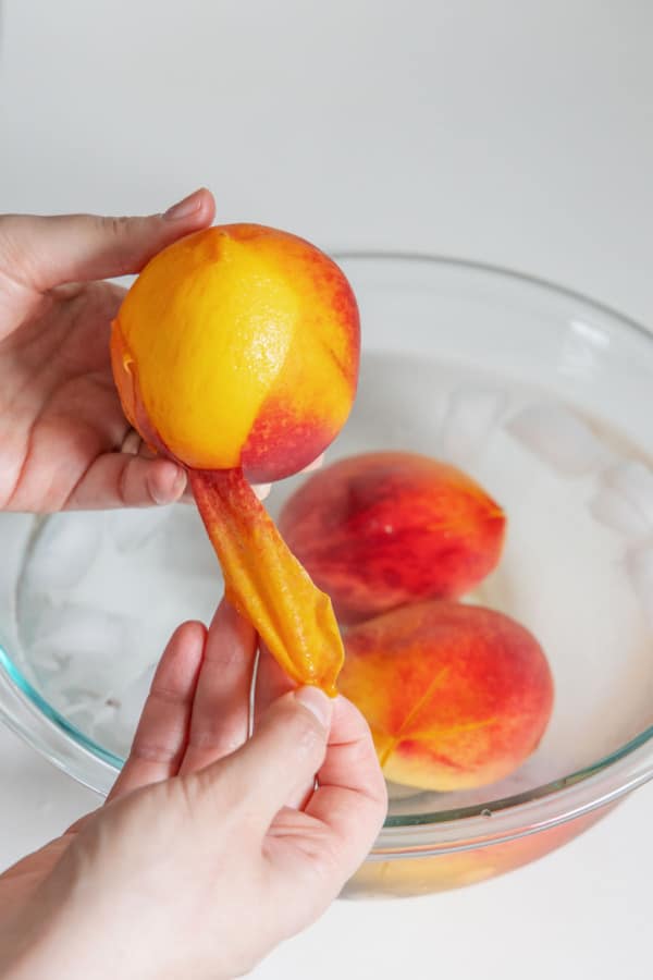 Peeling the skin off a peach after blanching it.