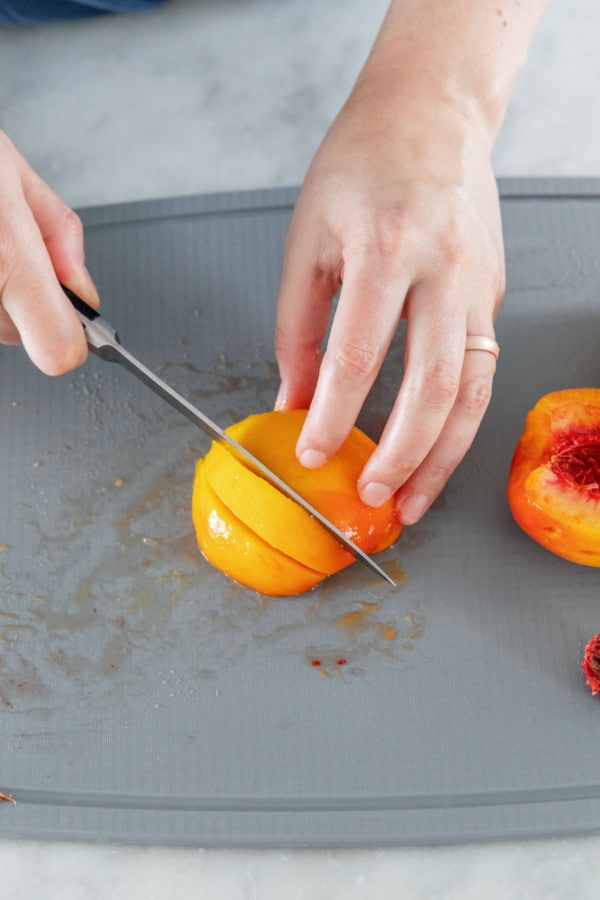 Cutting a peeled half peach into wedges.