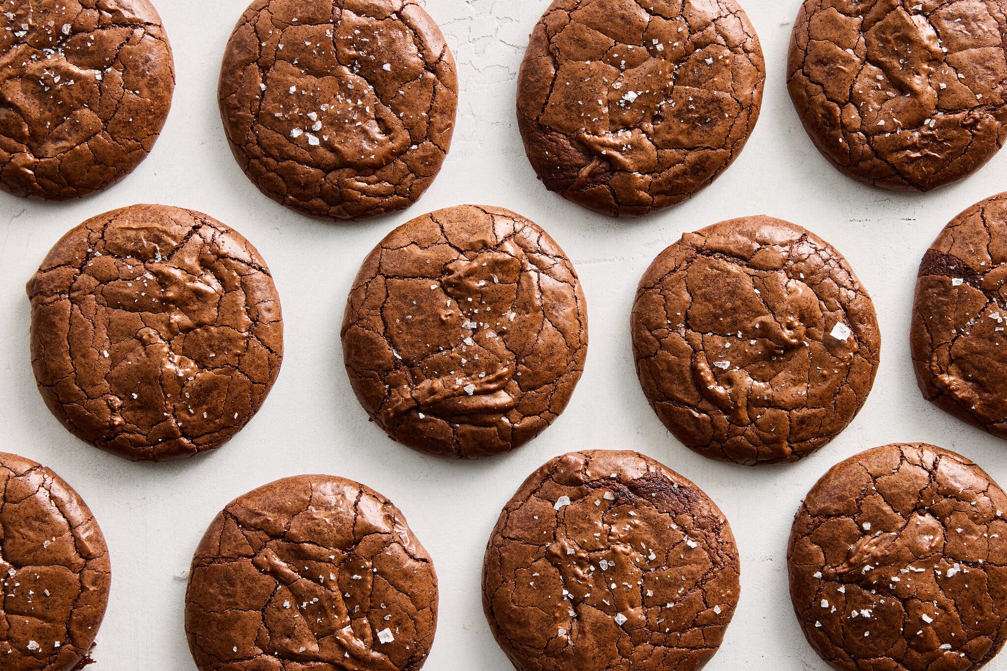 An overhead image of a dozen chocolate cookies topped with sprinkled sea salt.