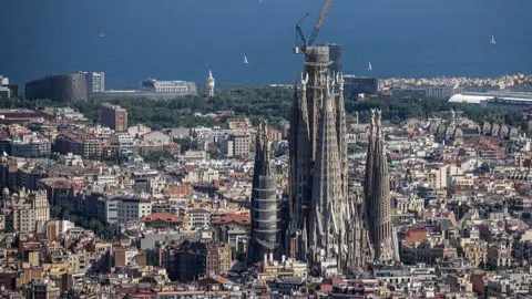 Getty Images The Sagrada Familia is pictured with a crane perched on top of it's central turret, with the rest of Barcelona stretched out behind the famous church.