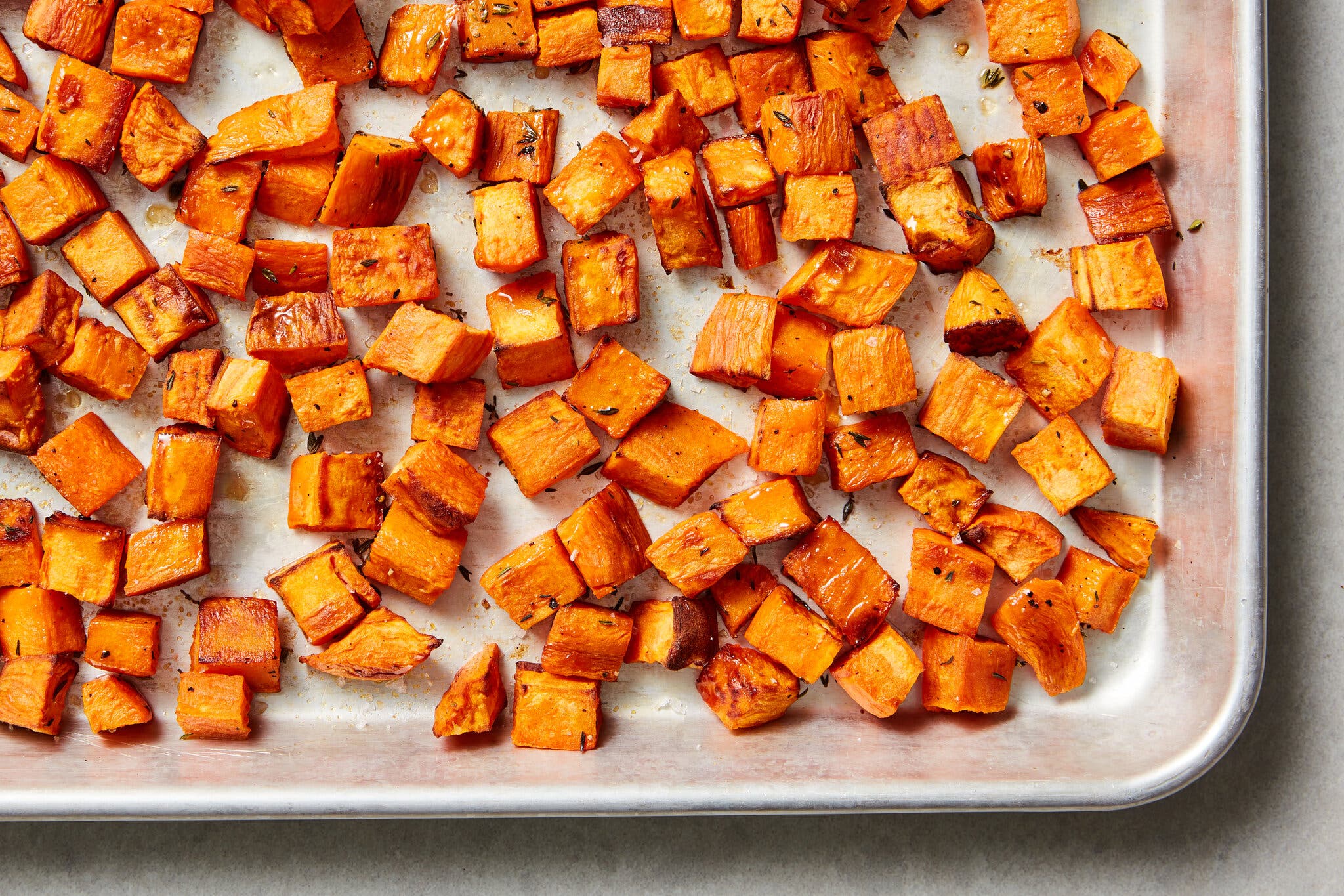 Cubes of roasted sweet potato sit on a baking sheet.