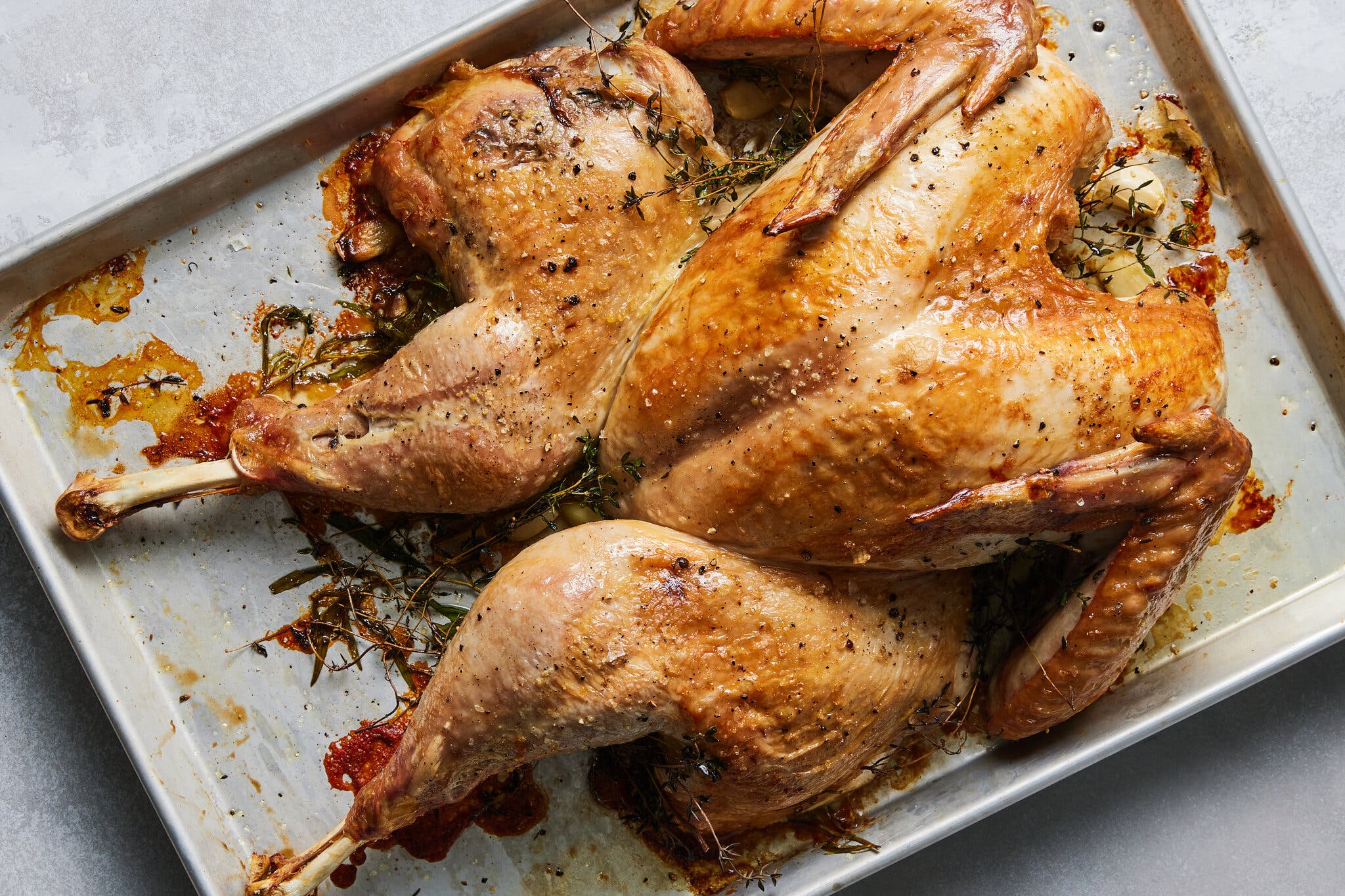 An overhead image of a spatchcocked turkey on a sheet pan.