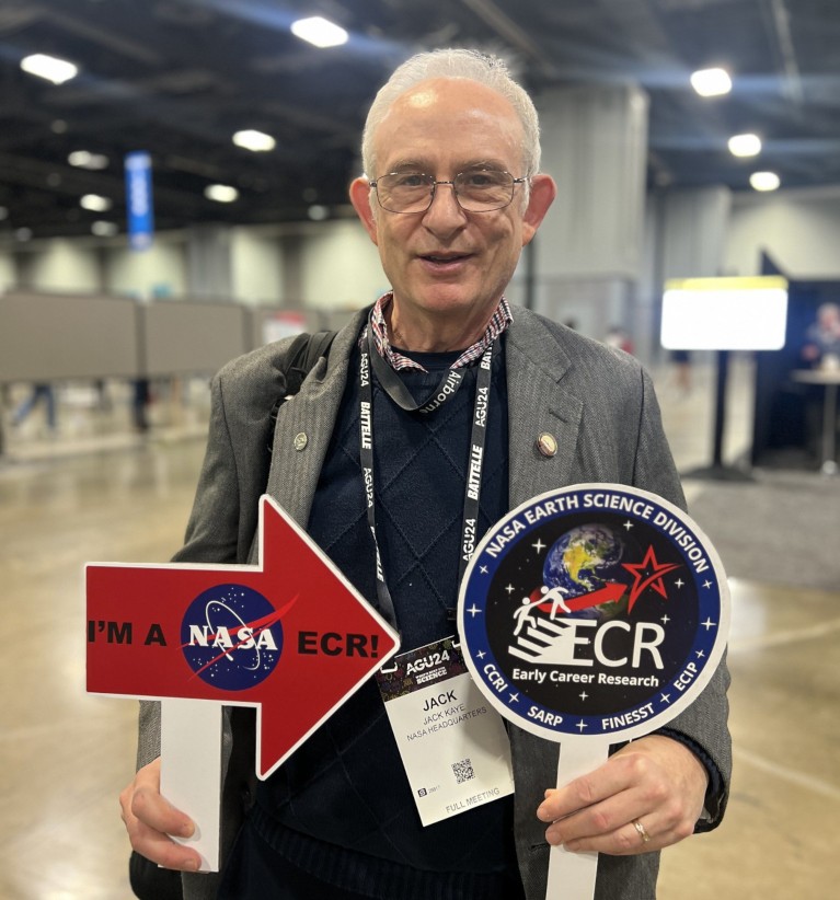 Jack Kaye in a convention centre holding NASA Early Career Researcher signs.